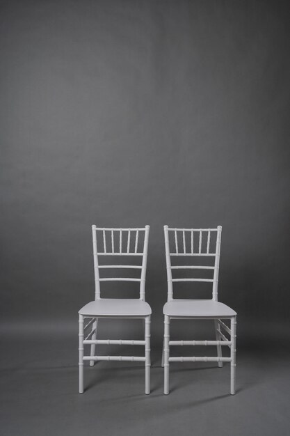 Two white chairs on grey backgroundxA