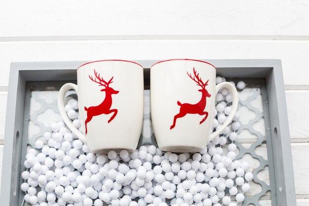 크리스마스 사슴 패턴이 있는 두 개의 흰색 커피 컵. 아름다운 휴가 유리 컵