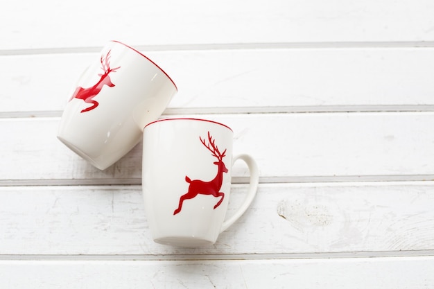 Two white coffee cups with a Christmas deer pattern. Beautiful holiday glass cups