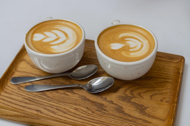 Two white cups of cappuccino on a wooden tray