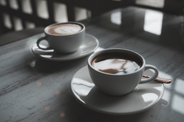 Two white cups of hot coffee on the table