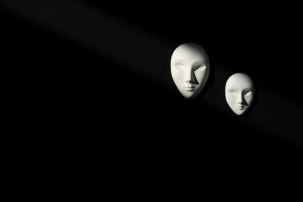검은 배경에 닫힌 눈을 가진 인간의 두 개의 흰색 석고 마스크