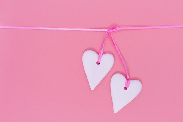 Two white hearts together on pink background. Holiday concept for wedding or Valentineâs Day.