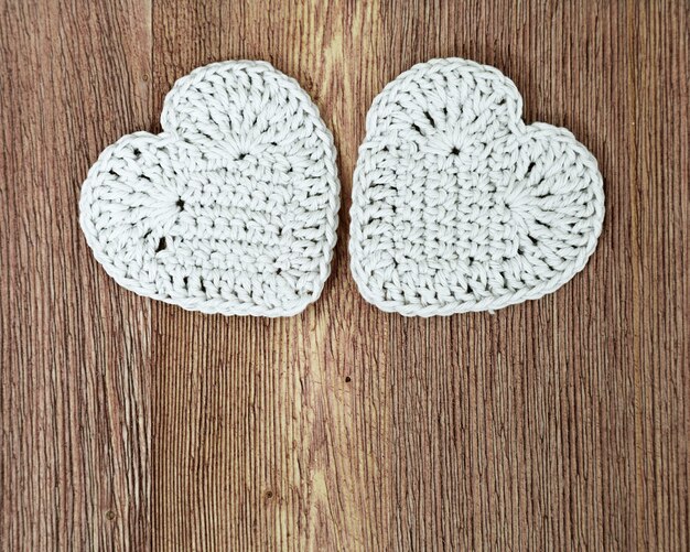 Two white knitted hearts on old wooden.