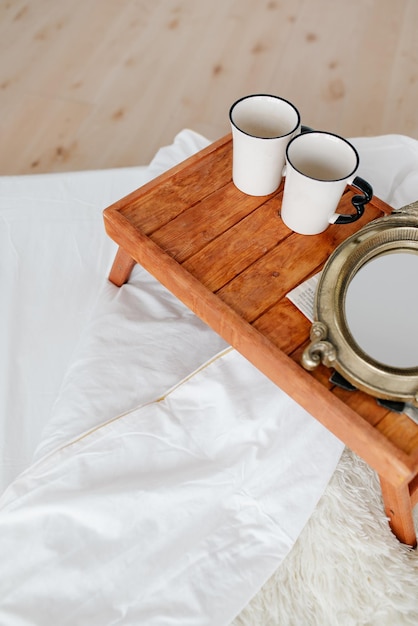 사진 아침 식사 트레이에 있는 흰색 머그 2개와 신문 흰색 침대