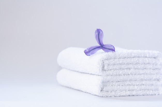 Two white neatly folded terry towels with a purple iris flower