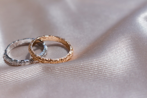 Two white and pink golden wedding rings on satin 