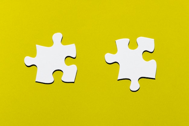 Photo two white puzzle piece on yellow backdrop