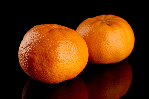 Two whole ripe tangerines on a black background