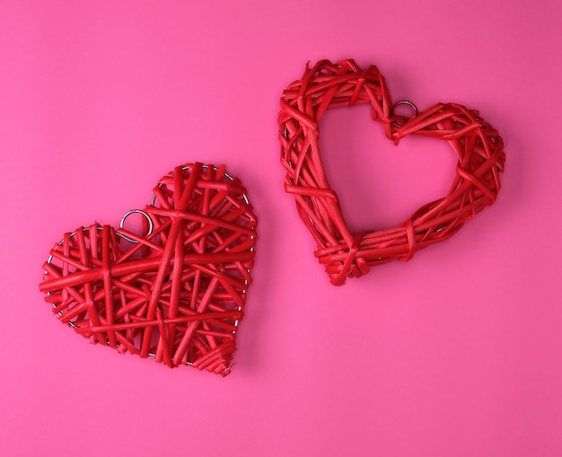 Two wicker red hearts on a pink background