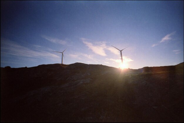 Photo two wind turbines against sunset