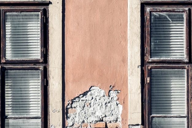 Foto due finestre sulla facciata di una vecchia casa con intonaco scrostato