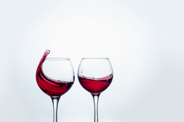 Two wine glasses in toasting gesture with big splashing at studio.