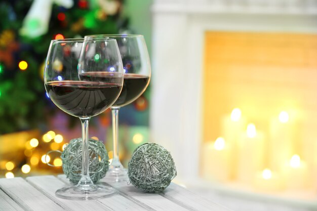 Two wine glasses with Christmas decor on fireplace background