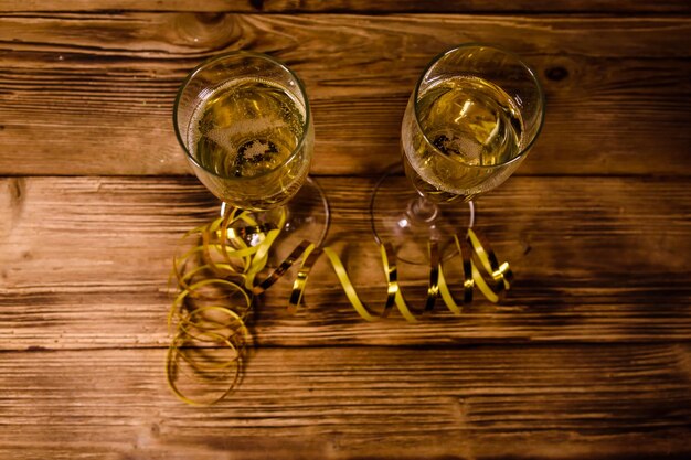 Two wineglasses with champagne and golden ribbon on rustic wooden table