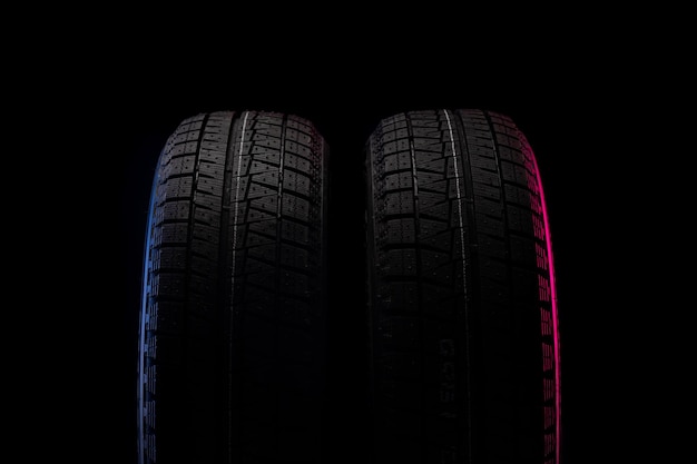 Two winter tires on a black background with redblue backlighting