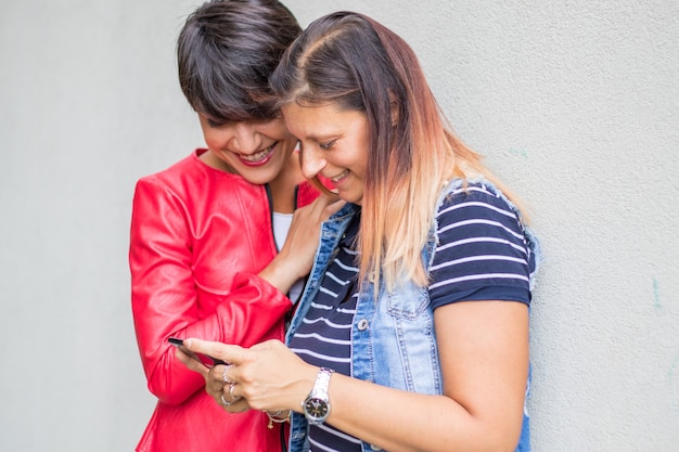 Two woman in casual dress are  looking tge callphone reading a message