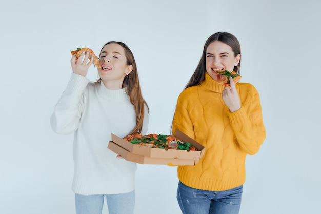 Two woman friends eating  pizza.