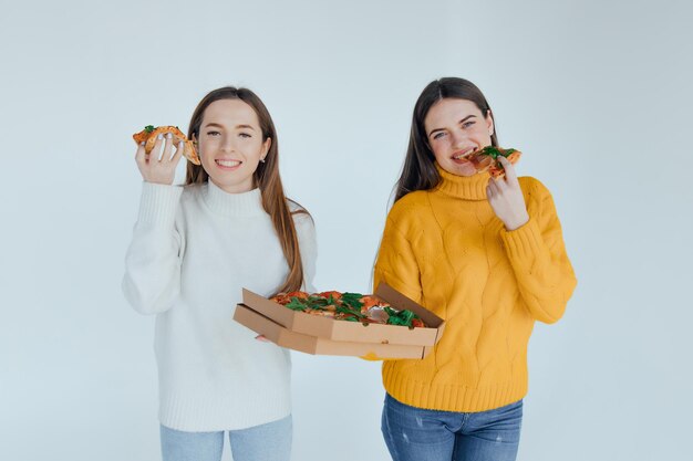 Two woman friends eating  pizza.