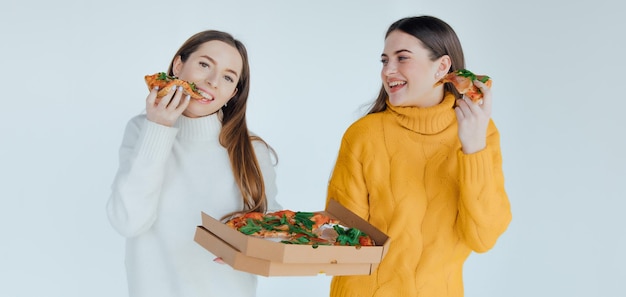 Two woman friends eating  pizza.