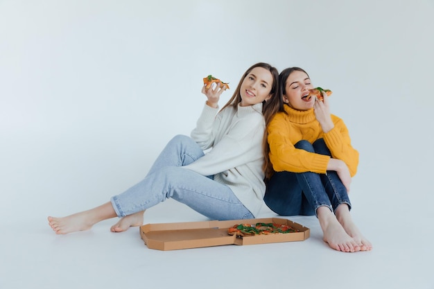 Two woman friends eating  pizza.