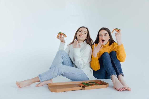 Two woman friends eating  pizza.