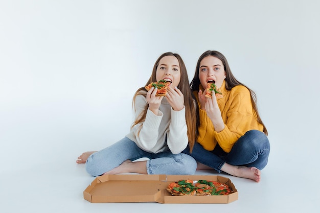 Photo two woman friends eating  pizza.