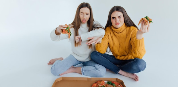 Two woman friends eating  pizza.