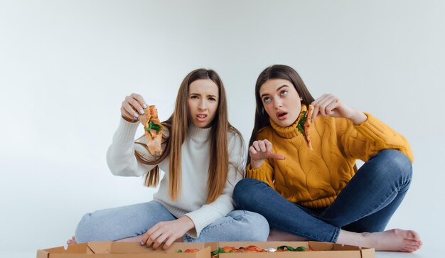 Two woman friends eating  pizza.