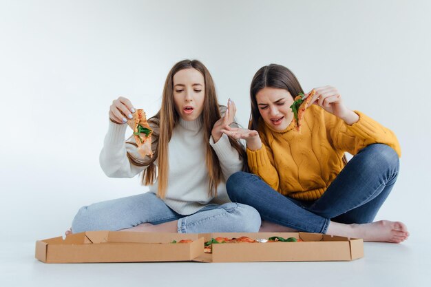 Two woman friends eating  pizza.