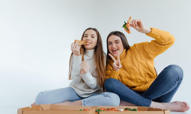 Two woman friends eating  pizza.