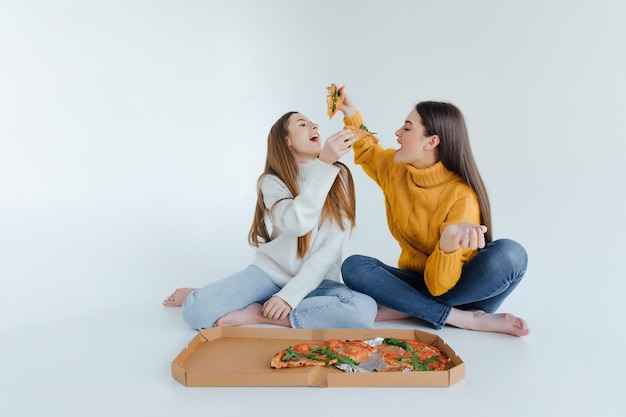 Two woman friends eating  pizza.