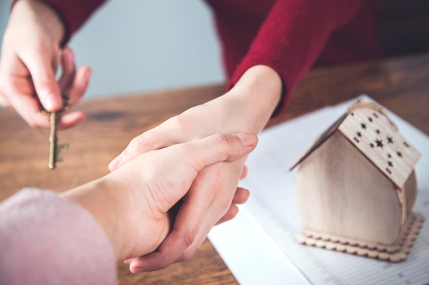 Foto due mani di donna modello di casa con documenti