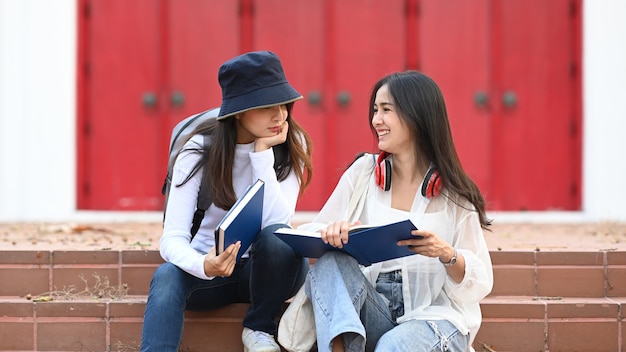 Two woman reading book and sitting in the park