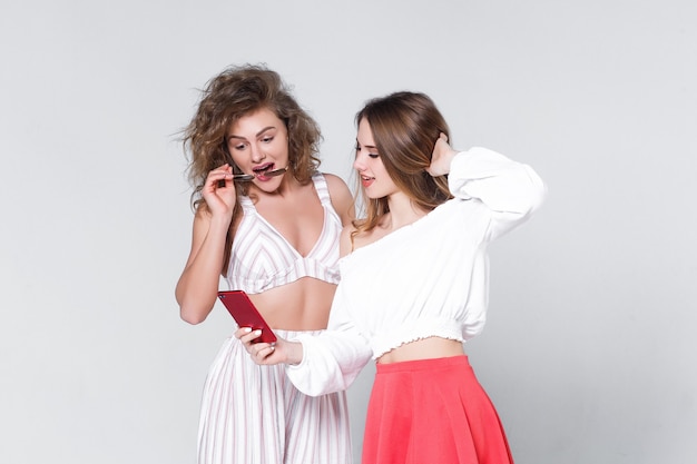 two woman with phone on hands posing to the camera!