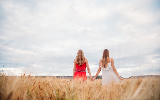 Two womans in dresses on a wheat field