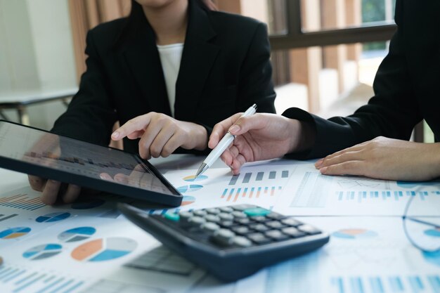 Two women are sitting at a table with a tablet and a calculator