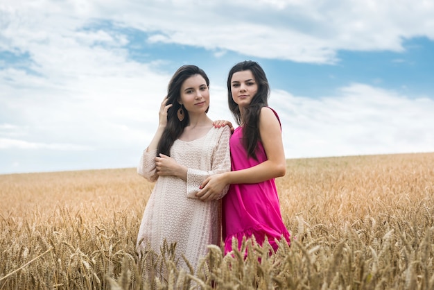 Two women in beauty dress possing at wheat field, summer day