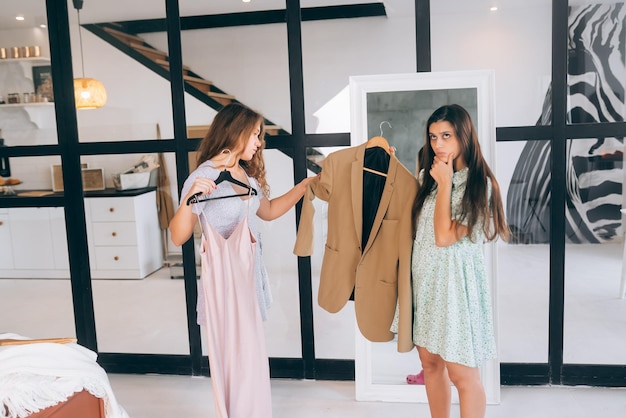 Photo two women choose and try on clothes at home