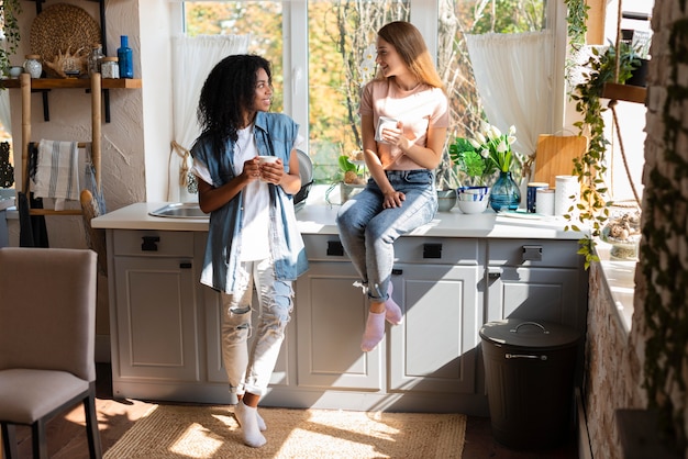 写真 キッチンでコーヒーを飲みながら会話する2人の女性