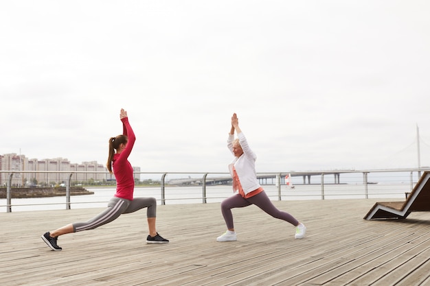 Due donne che fanno yoga sul molo