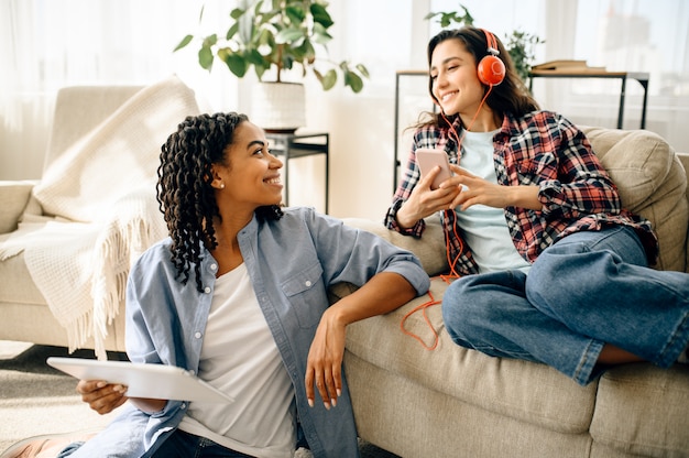 Two women enjoys listening to music indoors