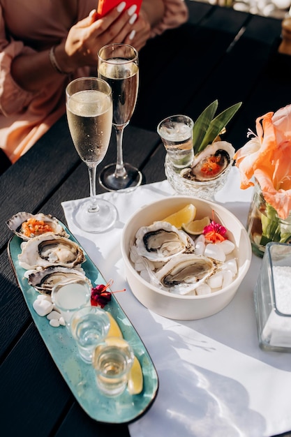 Two Women friends eating fresh oysters and drinking chilled prosecco wine on the summer sunset in restaurant Seafood delicacies