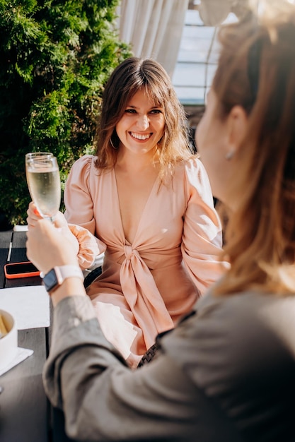 Due amiche che mangiano ostriche fresche e bevono vino prosecco freddo al tramonto estivo nel ristorante prelibatezze a base di pesce