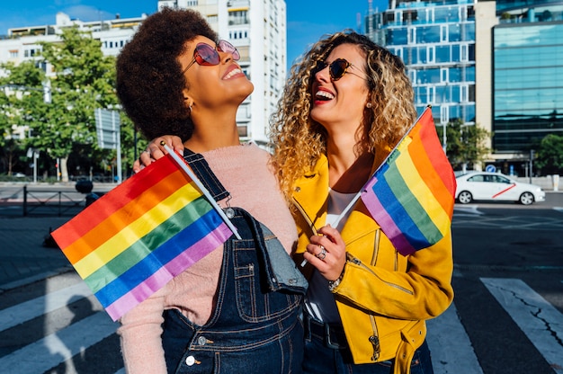 Two women friends hanging out in the city waving LGBT in Madrid city