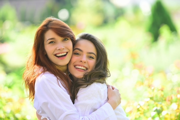 Two women friends laughing and hugging outdoors