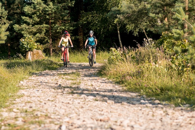 Две подруги катаются на велосипедах по бездорожью в лесу