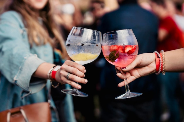 Due donne che tengono un gin tonic e brindano durante un festival musicale foto di alta qualità