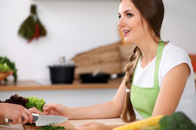 Two women is cooking in a kitchen Friends having a pleasure talk while preparing and tasting salad Friends Chef Cook concept