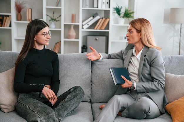two women is sitting on the sofa and talking casual and formal clothes
